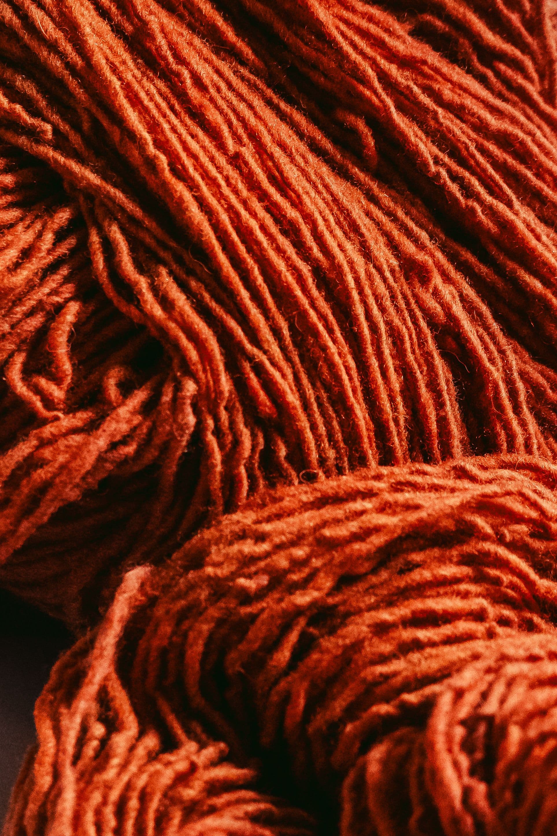 Close-up of vibrant orange wool yarn texture showcasing traditional craftsmanship.